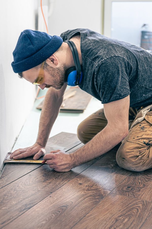 A male worker puts laminate flooring on the floor.